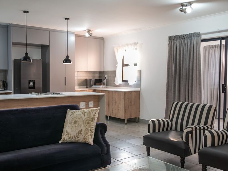 Modern open-plan living area featuring a contemporary kitchen with built-in cabinetry, a central island with a hob, and direct access to a balcony.