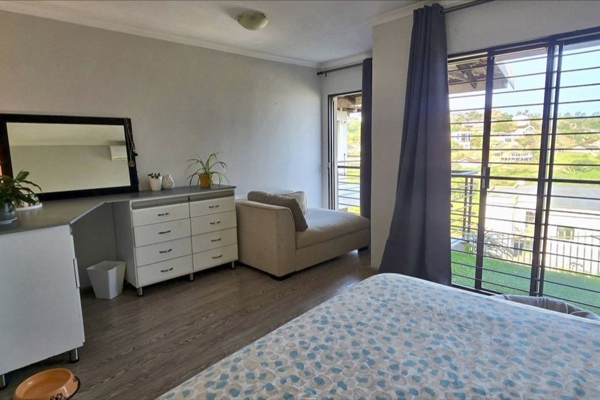 A bedroom featuring laminate flooring, cove cornicing, and a sliding glass door with security bars providing access to an outdoor area.