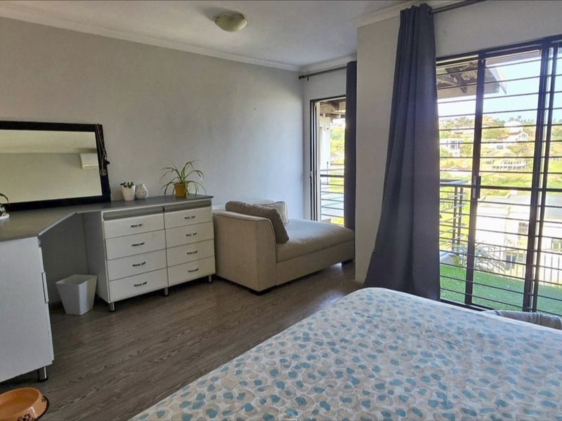 A bedroom featuring laminate flooring, cove cornicing, and a sliding glass door with security bars providing access to an outdoor area.