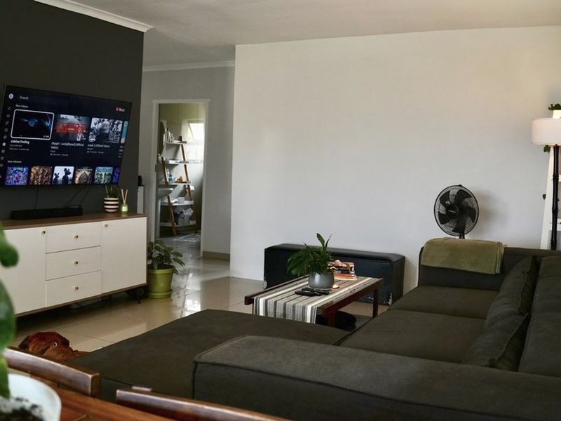 A comfortable living room featuring tiled flooring and a dark accent wall, providing a functional space for relaxation and entertainment.