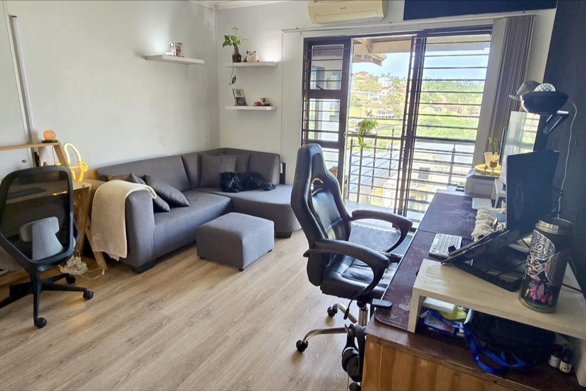A functional living room featuring laminate flooring, wall-mounted air conditioning, and a sliding glass door providing access to a balcony with scenic views.