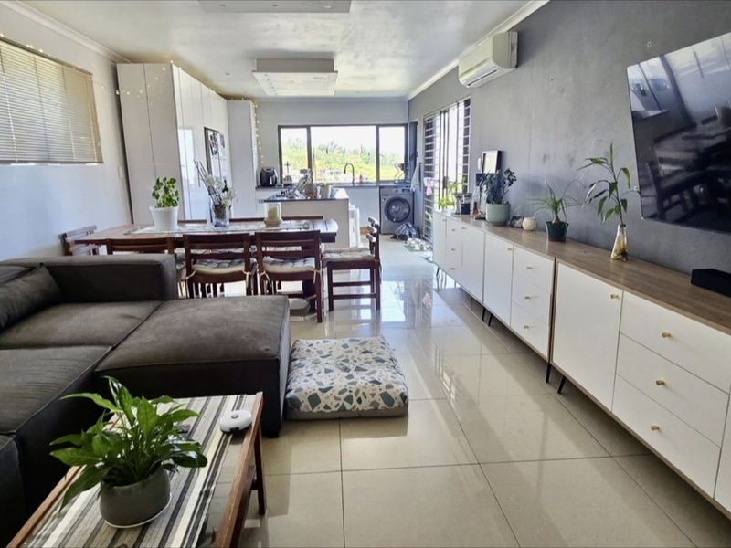 Spacious open-plan living and dining area featuring polished porcelain tiles, modern built-in cabinetry, and seamless flow to the kitchen and outdoor access.