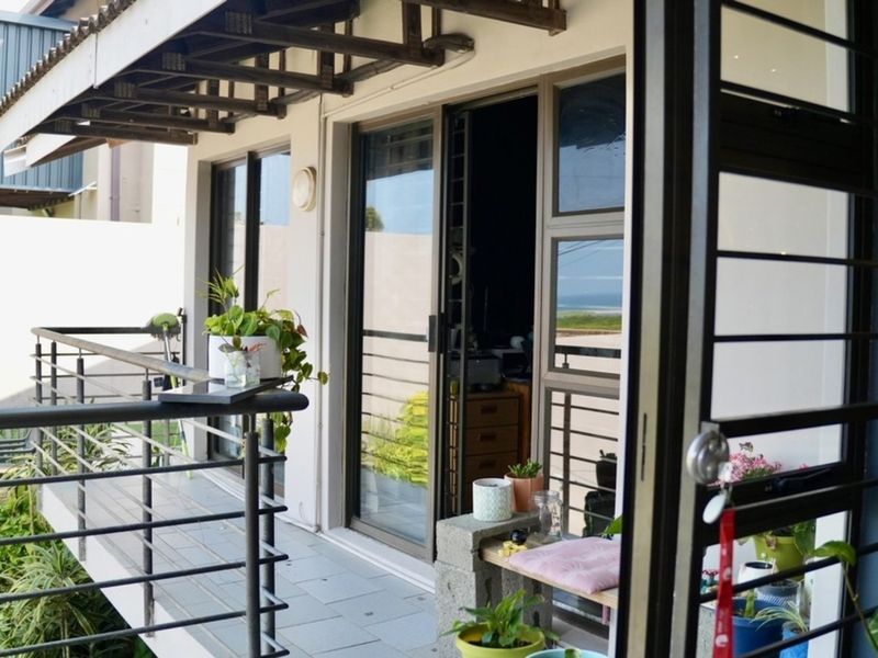 A covered balcony featuring tiled flooring, metal railings, and sliding glass doors providing access to the interior living space.