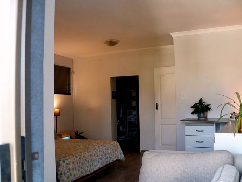 A bedroom featuring laminate flooring, built-in cupboard space, and cove cornicing, viewed from an adjacent room.