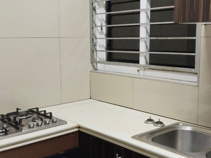 A functional kitchen area featuring a built-in gas hob, stainless steel sink with mixer tap, and tiled backsplash with security bars on the window.