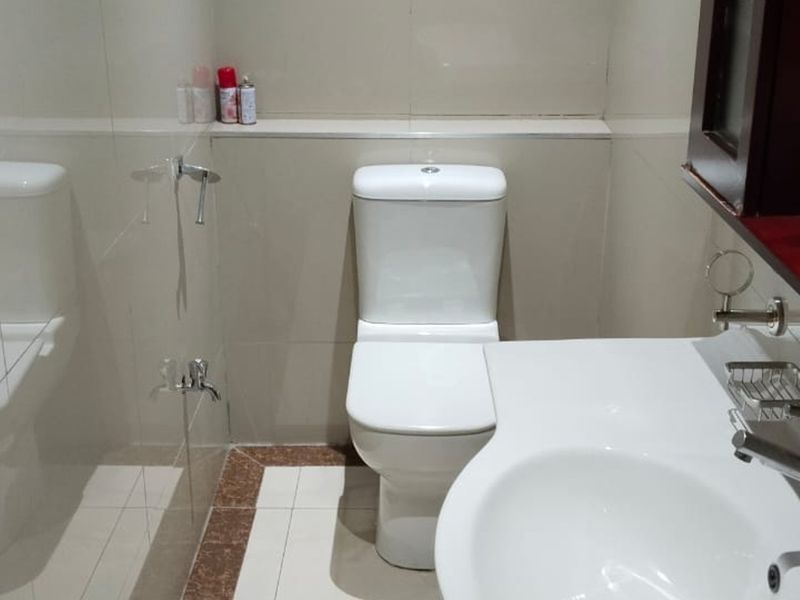 A functional bathroom featuring a white toilet, vanity basin with a modern mixer tap, and neutral wall and floor tiling.