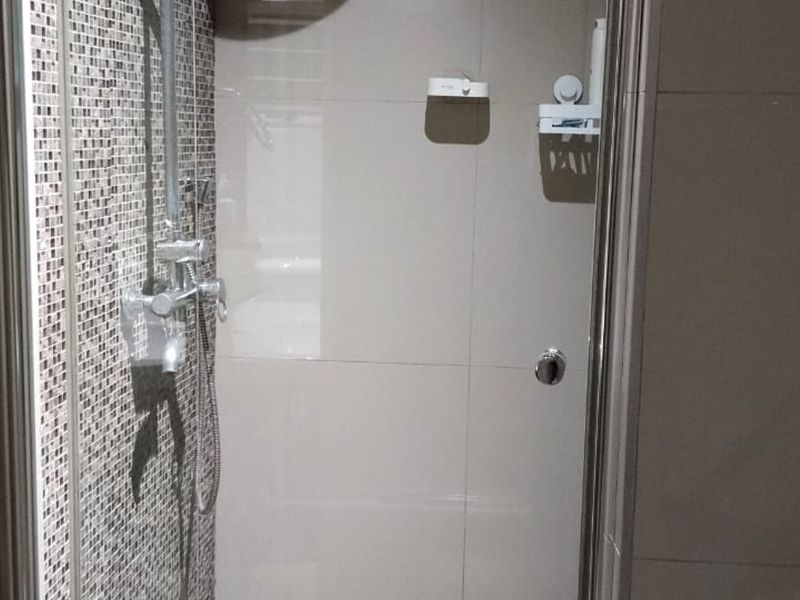 A functional shower enclosure featuring a mix of mosaic and large format wall tiles, equipped with a modern shower mixer and glass door.