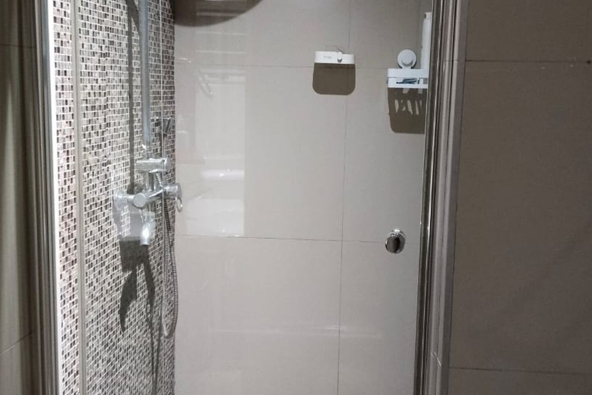 A functional shower enclosure featuring a mix of mosaic and large format wall tiles, equipped with a modern shower mixer and glass door.