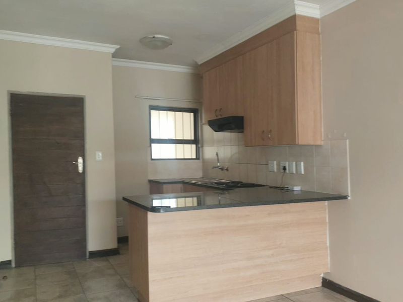 A functional kitchen featuring light wood cabinetry, granite countertops, an extractor fan, and tiled flooring, presenting a clean and neutral space.