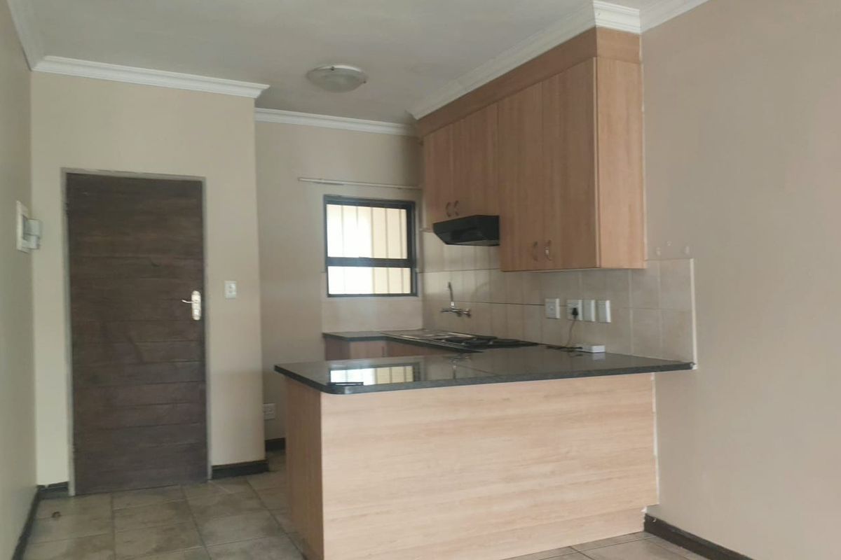 A functional kitchen featuring light wood cabinetry, granite countertops, an extractor fan, and tiled flooring, presenting a clean and neutral space.