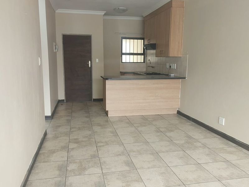 An open-plan living and kitchen area featuring tiled flooring, built-in cabinetry, a breakfast counter, and a functional kitchen workspace.