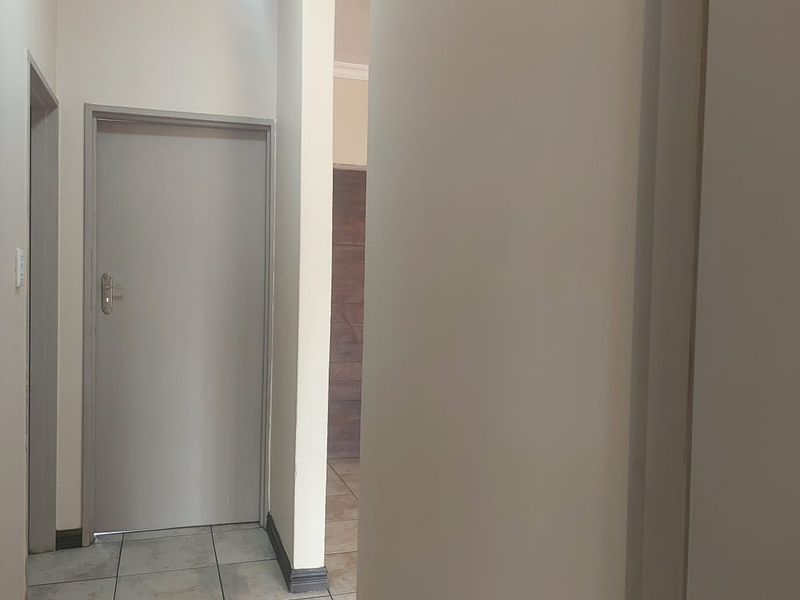A functional hallway featuring neutral wall finishes, tiled flooring, and internal doors providing access to adjacent rooms.