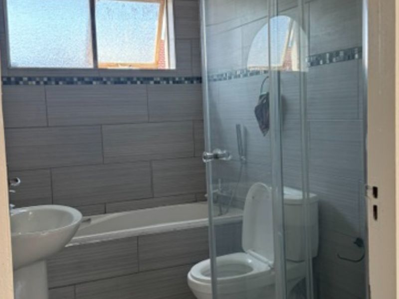 A functional bathroom featuring a pedestal basin, bathtub, and a separate shower enclosure with tiled walls and flooring.