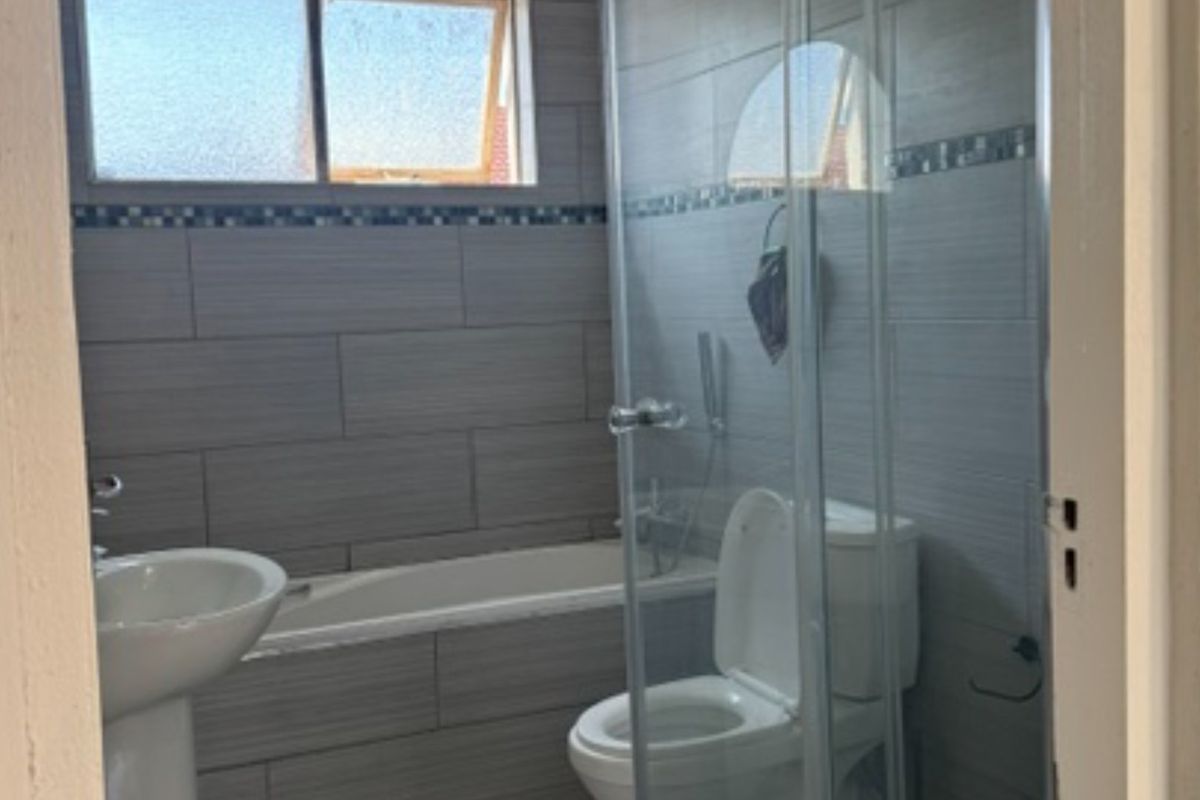A functional bathroom featuring a pedestal basin, bathtub, and a separate shower enclosure with tiled walls and flooring.