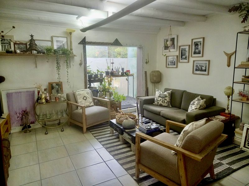 A cozy living room featuring exposed ceiling beams, tiled flooring, and a sliding glass door providing natural light and access to the outdoor area.