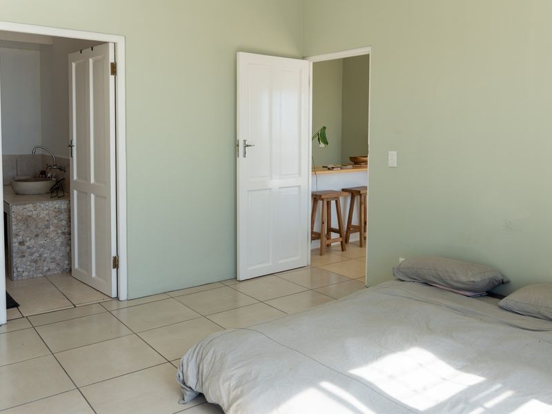 A bedroom featuring tiled flooring and direct access to an en-suite bathroom and an adjacent living area.