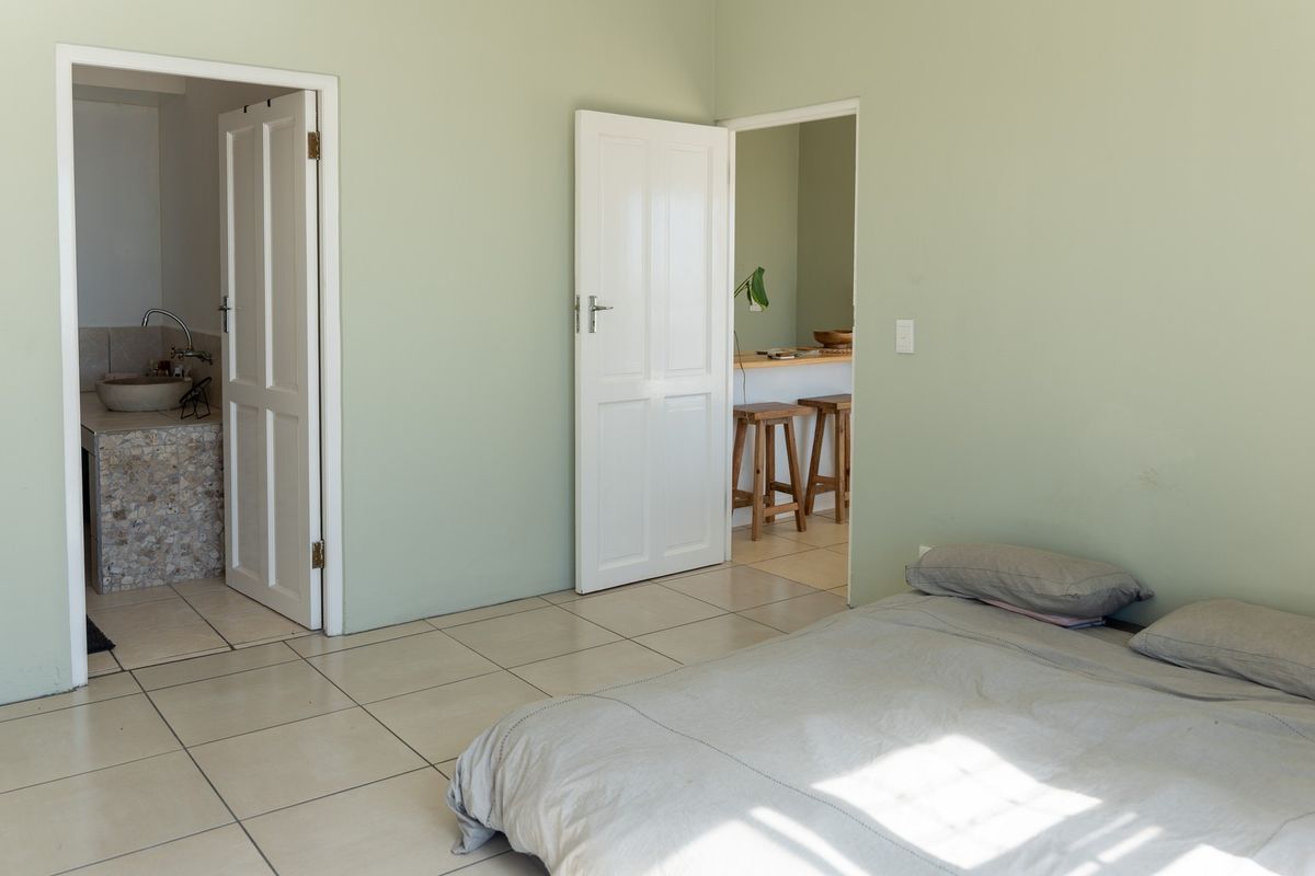 A bedroom featuring tiled flooring and direct access to an en-suite bathroom and an adjacent living area.