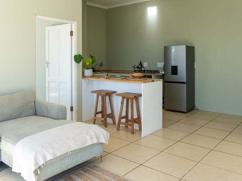 Open plan living area featuring a kitchen with a breakfast bar, tiled flooring, and neutral wall tones.