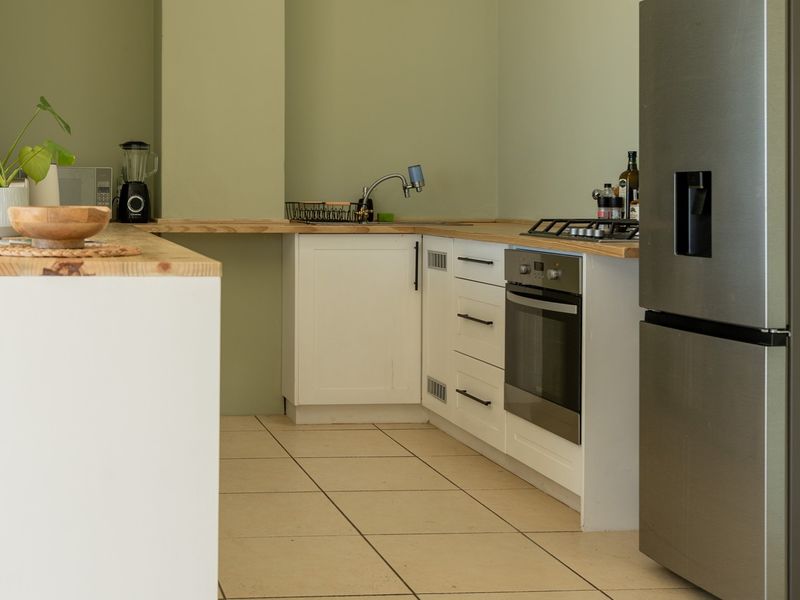 A functional kitchen featuring white cabinetry, wooden countertops, a built-in oven with gas hob, and tiled flooring.