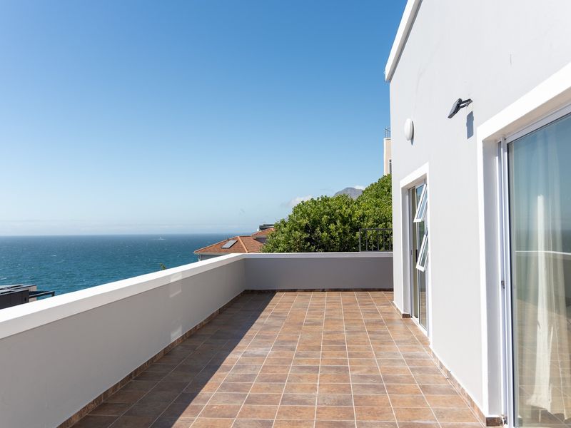 Spacious balcony featuring tiled flooring, a protective parapet wall, and sliding glass doors, offering expansive ocean views.