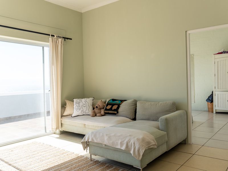 A bright living room featuring tiled flooring and a large sliding glass door that provides access to an outdoor balcony area.