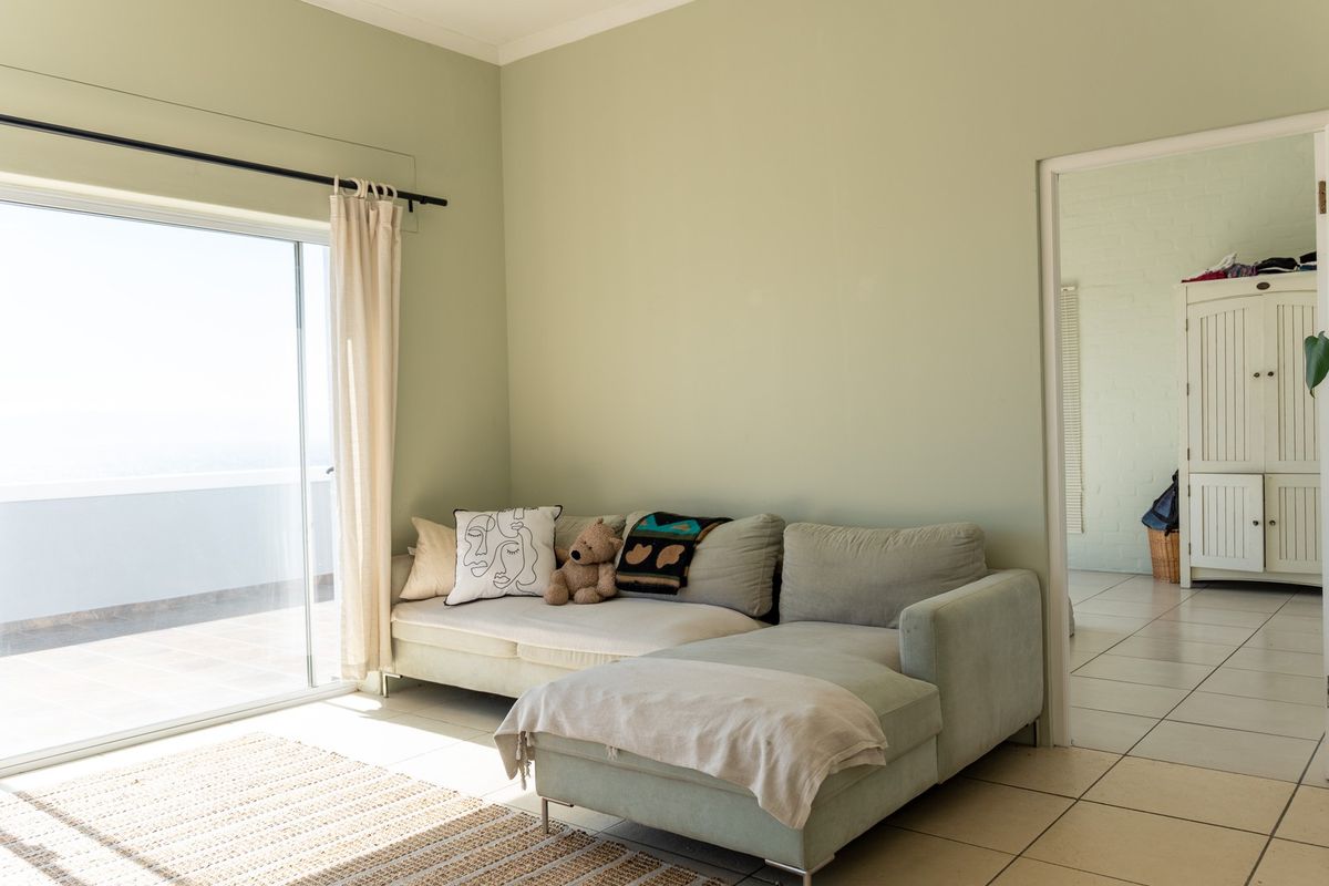 A bright living room featuring tiled flooring and a large sliding glass door that provides access to an outdoor balcony area.