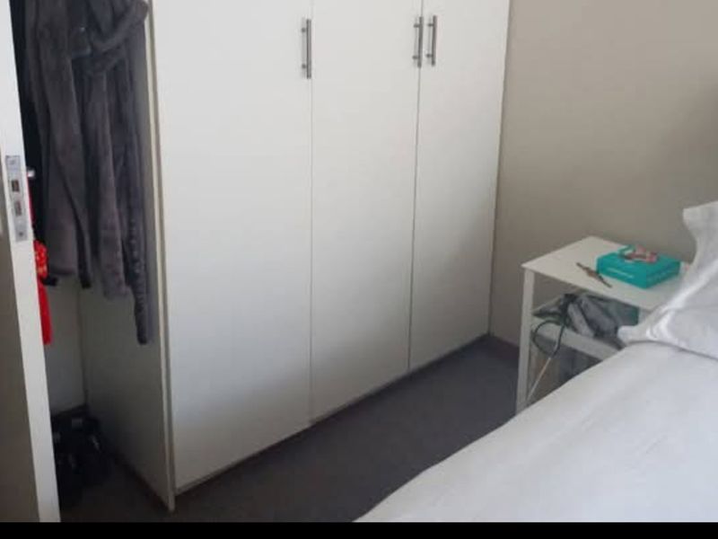 A bedroom featuring a built-in white wardrobe with modern handles, providing functional storage space.