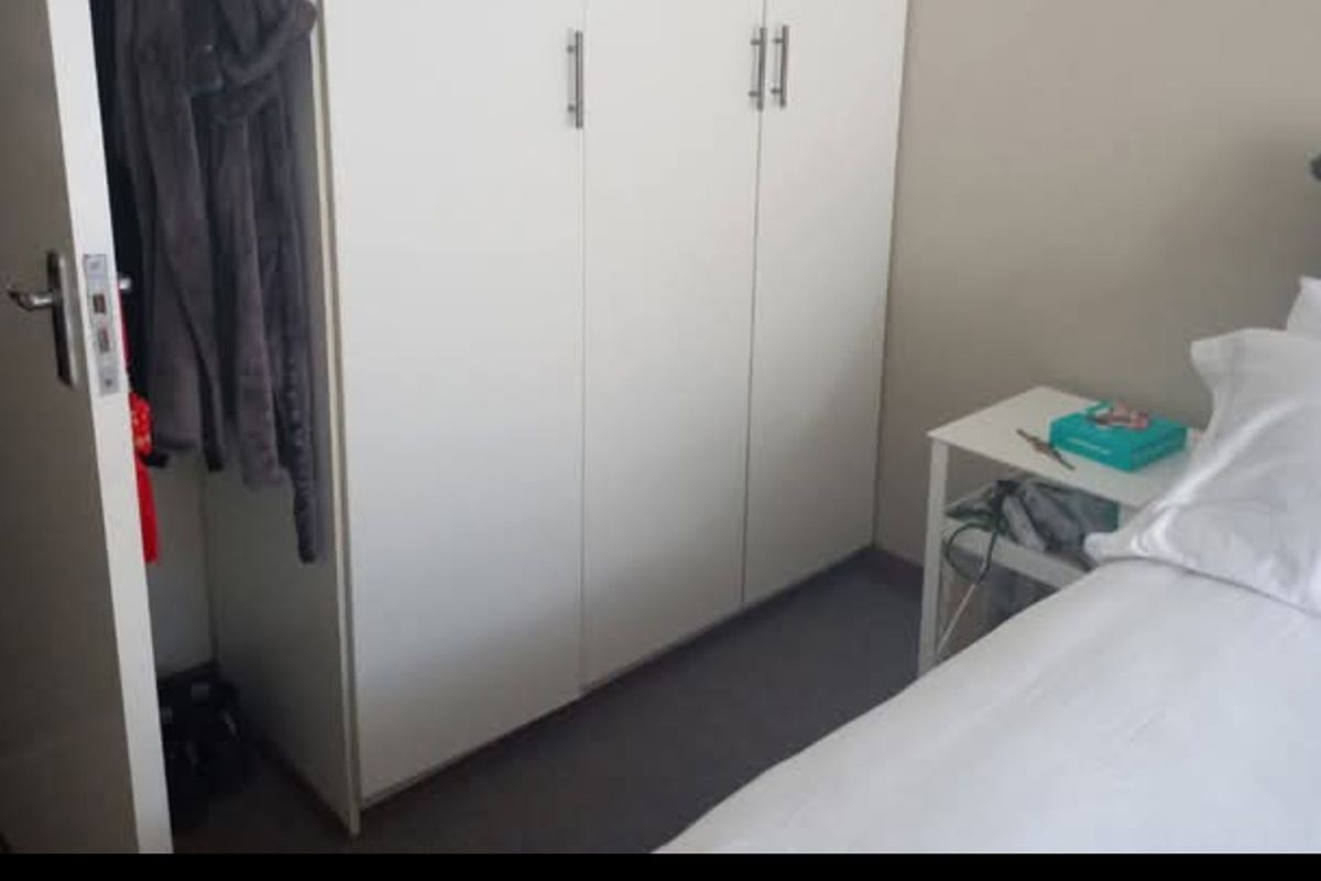 A bedroom featuring a built-in white wardrobe with modern handles, providing functional storage space.