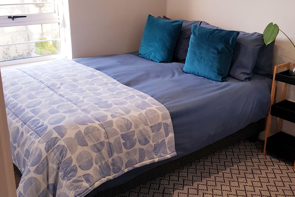 A cozy bedroom featuring a window with an aluminium frame, providing natural light to the space.