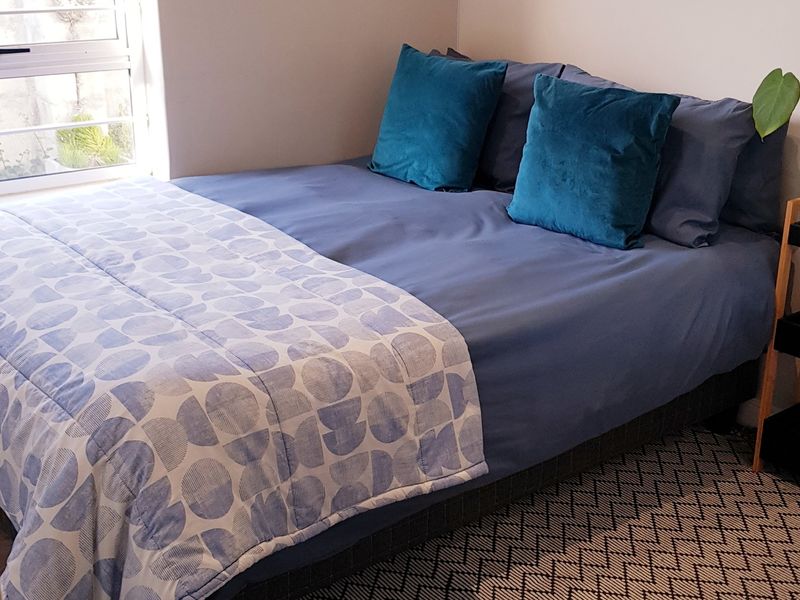 A cozy bedroom featuring a window with an aluminium frame, providing natural light to the space.