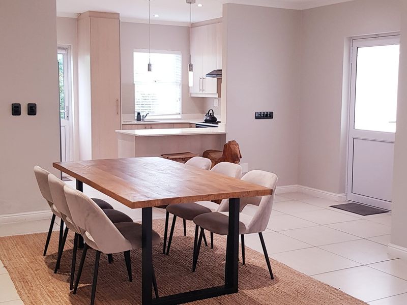Open-plan dining area featuring tiled flooring and recessed lighting, seamlessly connected to a modern kitchen with built-in cabinetry and functional workspace.