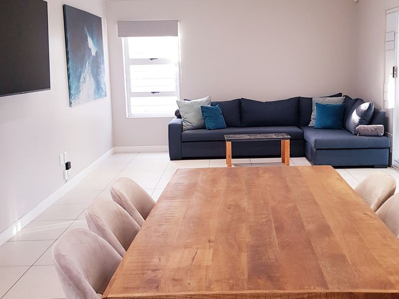 Spacious open-plan living and dining area featuring neutral tiled flooring and large sliding glass doors providing access to the outdoor space.