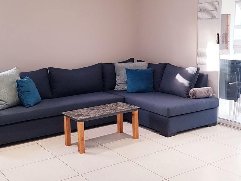 A bright living room featuring neutral tiled flooring and a large sliding glass door providing natural light and access to the outdoor area.