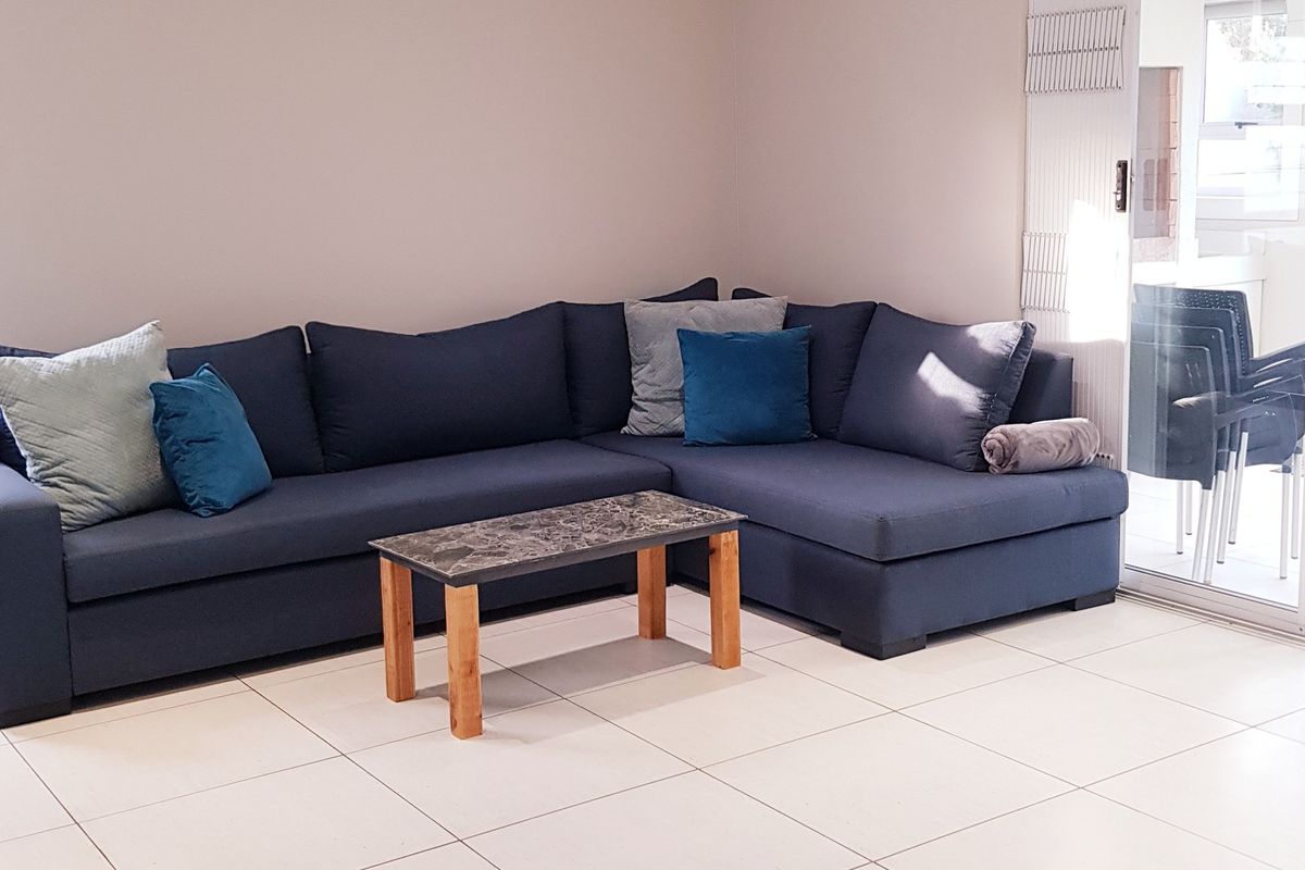 A bright living room featuring neutral tiled flooring and a large sliding glass door providing natural light and access to the outdoor area.