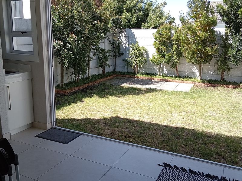 Covered patio area featuring a built-in braai, tiled flooring, and direct access to a private garden with a boundary wall.