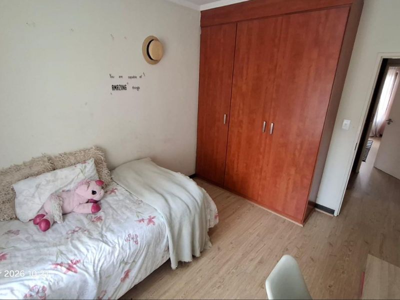A bedroom featuring laminate flooring and a large built-in wooden wardrobe, offering functional storage space.