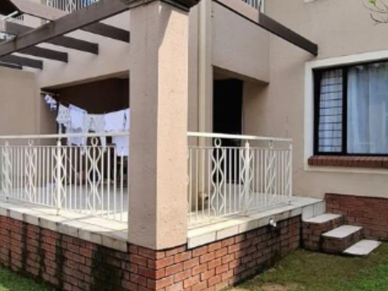 A ground floor patio area featuring a pergola, metal balustrade, and brick base, providing direct access to the apartment exterior.