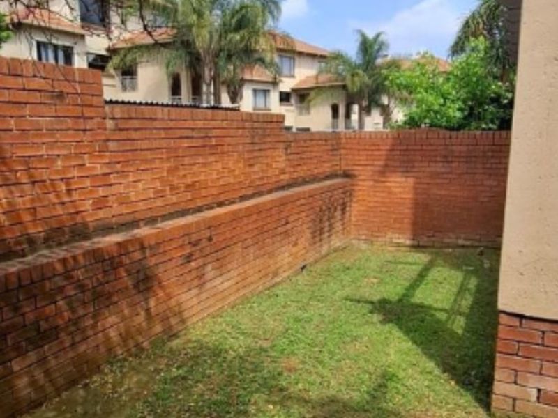 A private rear garden area featuring a brick boundary wall and a small lawn space, offering potential for landscaping improvements.
