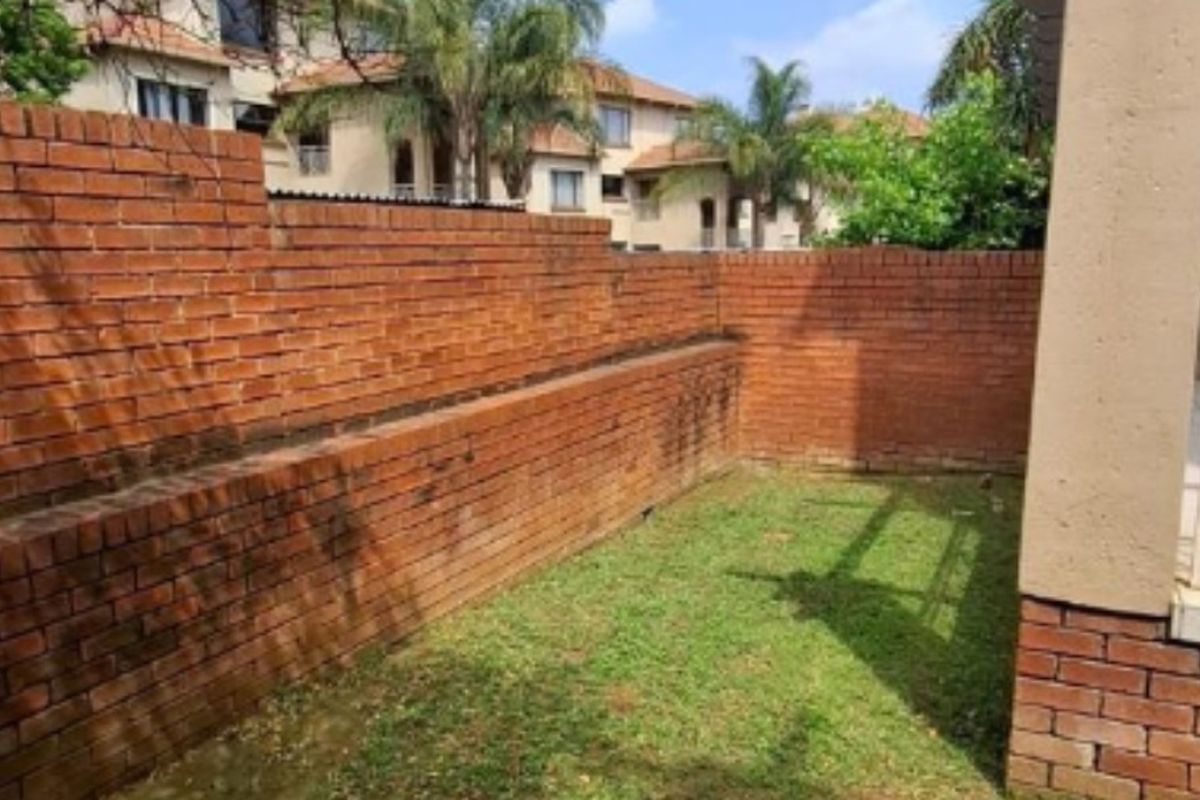 A private rear garden area featuring a brick boundary wall and a small lawn space, offering potential for landscaping improvements.