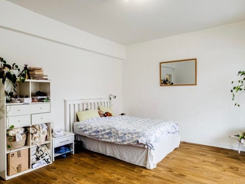 A bright and spacious bedroom featuring durable laminate flooring and neutral white walls, offering a clean and versatile living space.