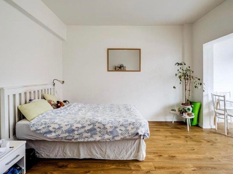 A bright and spacious bedroom featuring durable laminate flooring and a large window that allows for ample natural light.