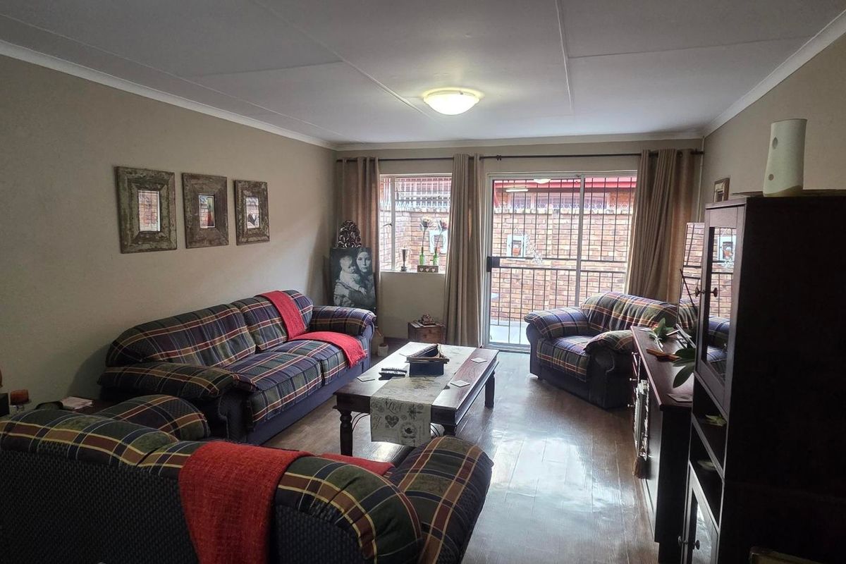 A comfortable living room featuring laminate flooring, a ceiling light fixture, and a sliding glass door providing access to the exterior.