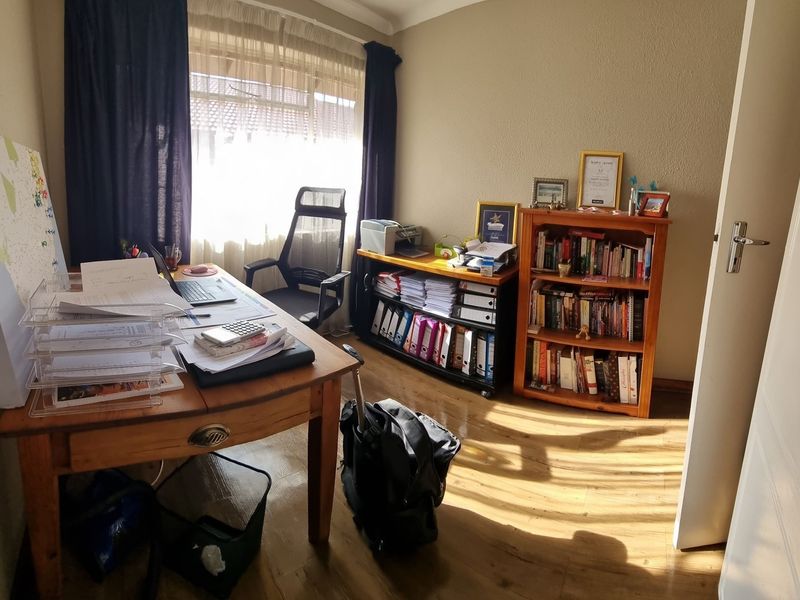 A functional home office space featuring laminate flooring and natural light, suitable for a dedicated workspace or study area.