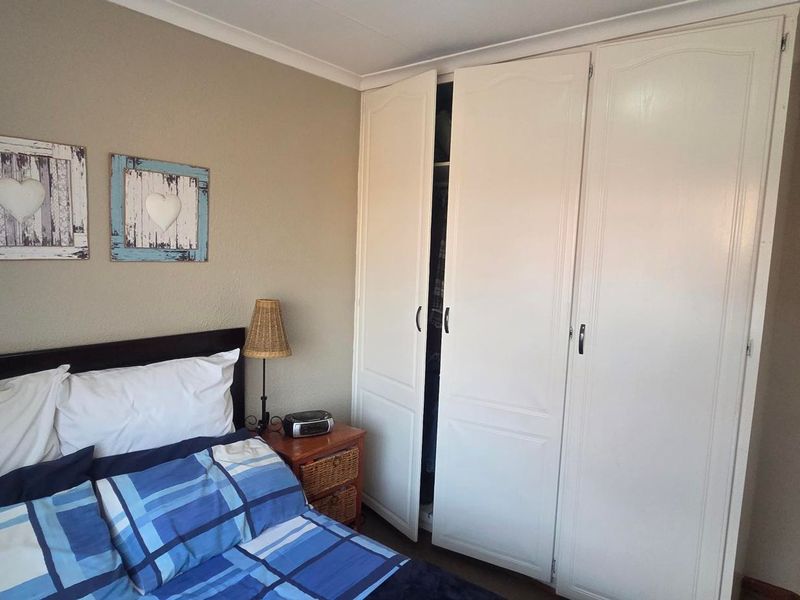 A bedroom featuring a white built-in wardrobe with classic panel detailing and cove cornice finishes.