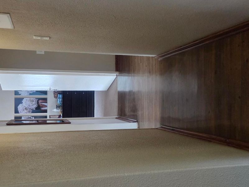A clean, empty hallway featuring hardwood flooring and neutral wall finishes, providing access to adjacent rooms.