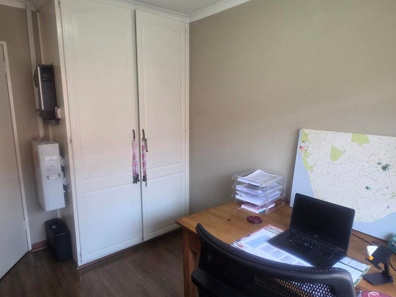 A functional bedroom featuring laminate flooring, a built-in wardrobe, and a wall-mounted inverter system.