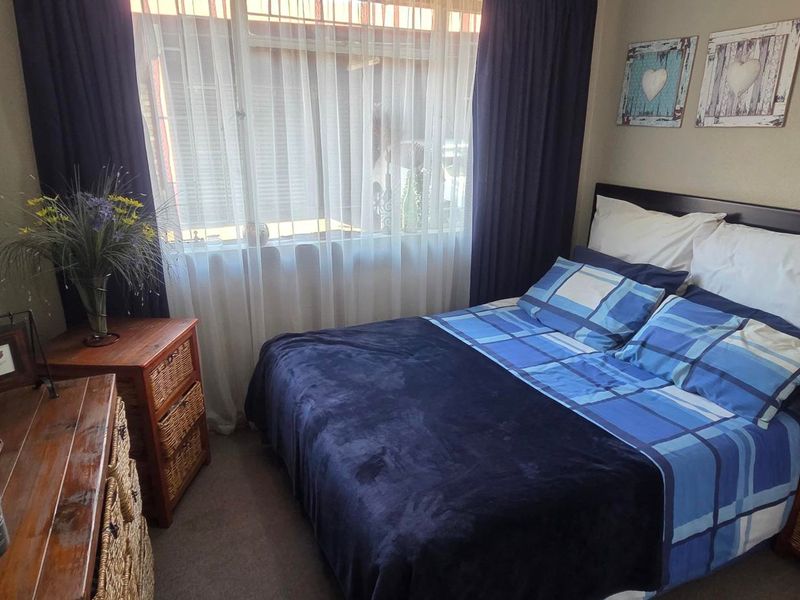 A cozy bedroom featuring carpeted flooring and large windows with installed curtain rails, providing natural light and a comfortable living space.