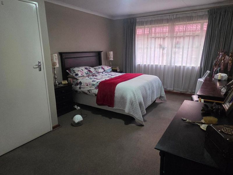 A standard bedroom featuring carpeted flooring and large windows with curtain rails, providing a functional and comfortable living space.