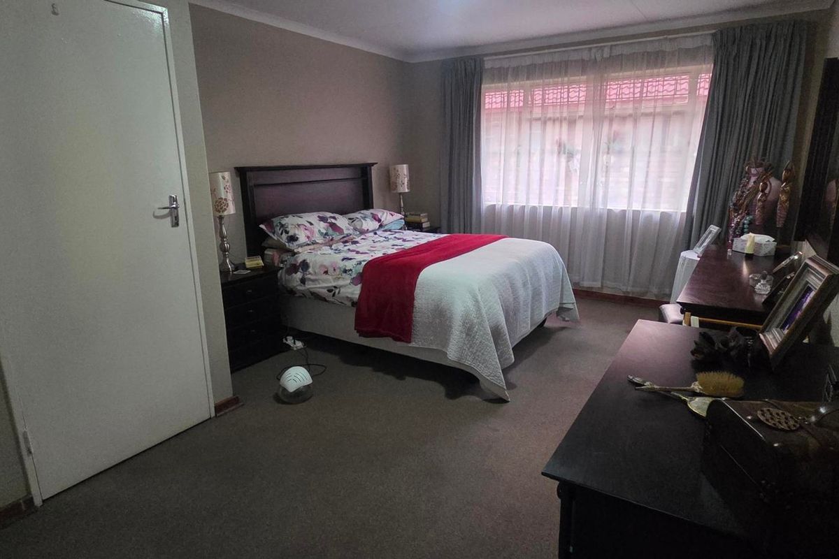 A standard bedroom featuring carpeted flooring and large windows with curtain rails, providing a functional and comfortable living space.