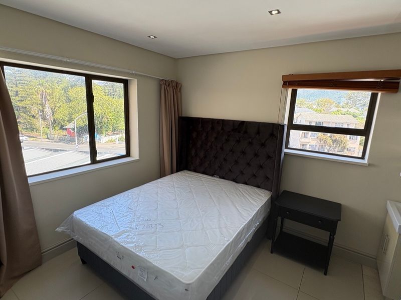 A well-lit bedroom featuring tiled flooring, recessed downlights, and a convenient built-in vanity basin, offering a functional and comfortable living space.